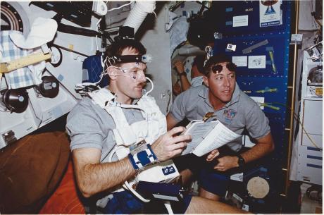 Connected to biomedical sensors, astronaut Steven L. Smith, mission specialist, serves as test subject for one of the flight's 15 Detailed Supplementary Objectives (DSO). Astronaut Michael A. Baker, mission commander, monitors the test on the Space Shuttle Endeavour's middeck. This test deals with the visual-vestibular integration as a function of adaptation to Spaceflight. Baker and Smith were joined by four other NASA astronauts for eleven days aboard the Endeavour in Earth-orbit, in support of the Space Radar Laboratory-2 (SRL-2) mission. (NASA caption, STS068-021-023). 
