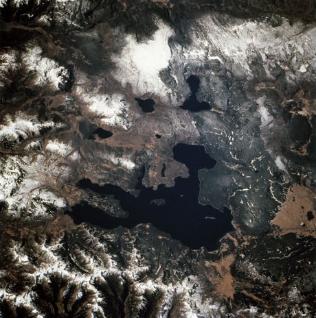 Photographed through the Space Shuttle Endeavour's flight windows, this 70mm frame centers on Yellowstone Lake in the Yellowstone National Park. North will be at the top if picture is oriented with series of sun glinted creeks and river branches at top center. The lake, at 2,320 meters (7,732 feet) above sea level, is the largest high altitude lake in North America. East of the park part of the Absaroka Range can be traced by following its north to south line of snow capped peaks. Jackson Lake is southeast of Yellowstone Park, and the connected Snake River can be seen in the lower left corner. Yellowstone, established in 1872 is the world's oldest national park. It covers an area of 9,000 kilometers (3,500 square miles), lying mainly on a broad plateau of the Rocky Mountains on the Continental Divide. It's average altitude is 2,440 meters (8,000 feet) above sea level. The plateau is surrounded by mountains exceeding 3,600 meters (12,000 feet) in height. Most of the plateau was formed from once-molten lava flows, the last of which is said to have occurred 100,000 years ago. Early volcanic activity is still evident in the region by nearly 10,000 hot springs, 200 geysers and numerous vents found throughout the park.(NASA caption, STS068-247-061) 